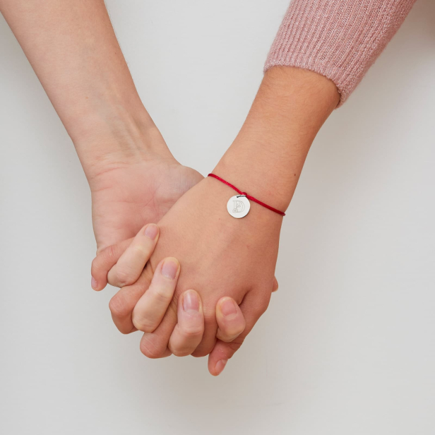 Photo du bijou porté sur un poignet de jeune fille. Le bijou est un bracelet cordon personnalisé enfant avec initiale florale