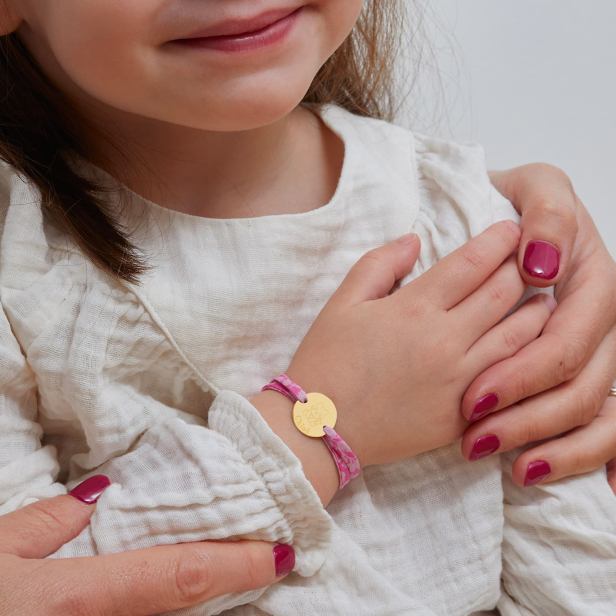 Bracelet personnalisé en plaqué or, avec une illustration de chat, porté sur le poignet d'une jeune fille.